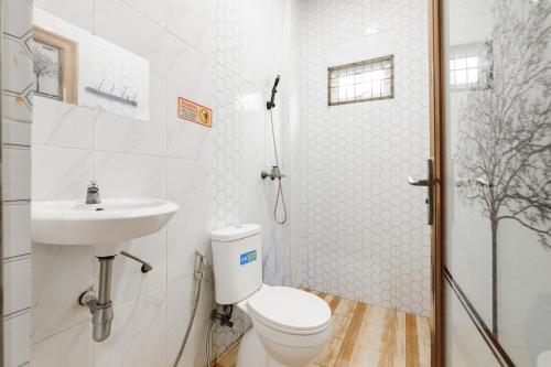 a white bathroom with a toilet and a sink at RedDoorz Lotte near PTC MALL in Palembang