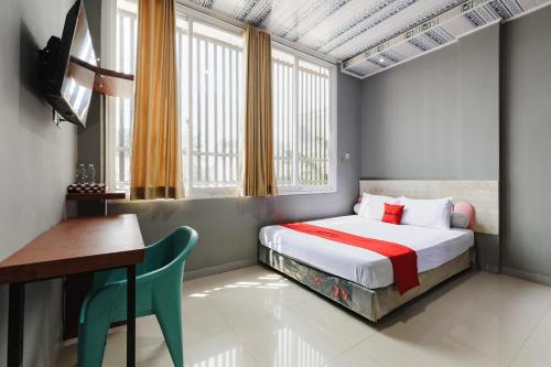 a bedroom with a bed and a table and a desk at RedDoorz Lotte near PTC MALL in Palembang