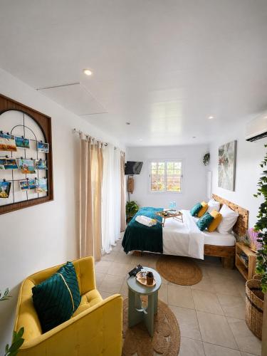 a bedroom with a bed and a yellow couch at Le SeaZen Lodge in Sainte-Anne