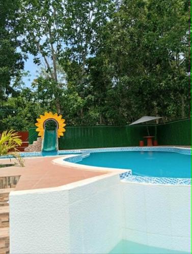 a swimming pool with a sunflower next to a fence at Ella Garden Resort in Mag-ag