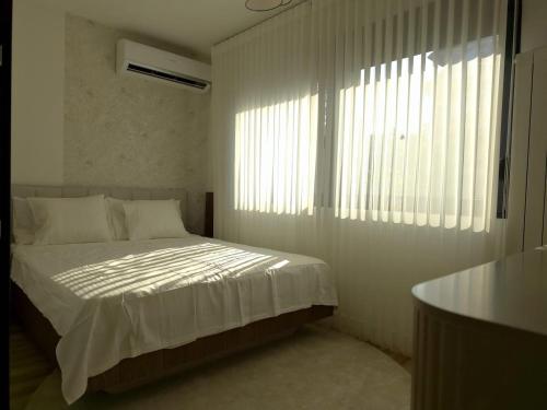 a bedroom with a bed with white sheets and a window at Negotin Centar Boutique Residence in Negotin