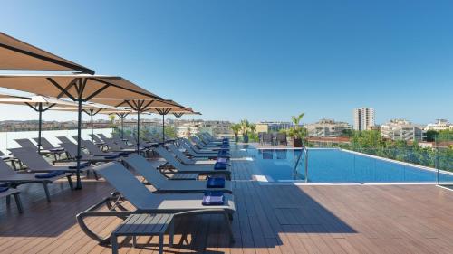 a row of lounge chairs next to a swimming pool at H10 Vintage Salou - Adults Only in Salou