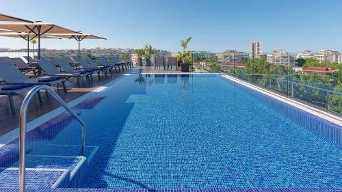 a large swimming pool with lounge chairs and umbrellas at H10 Vintage Salou - Adults Only in Salou