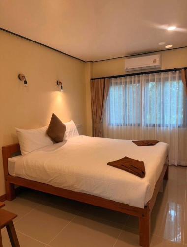 a bedroom with a white bed with a window at PnppGreenhill in Ko Phangan