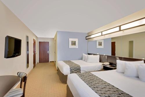 a hotel room with two beds and a flat screen tv at Microtel Inn and Suites by Wyndham - Geneva in Geneva