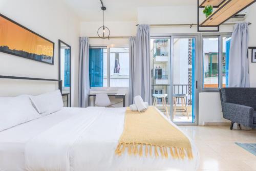 a bedroom with a white bed and a table and chairs at Factory Studio in Mar Mikhael in Al Mudawwar