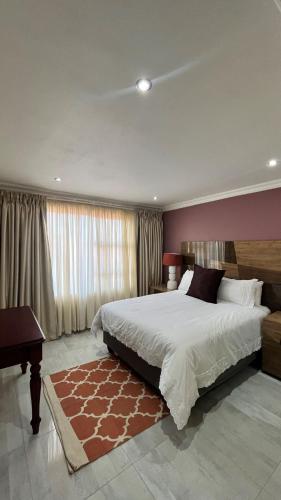 a bedroom with a large bed and a large window at Yolaan Guesthouse in Sterkspruit