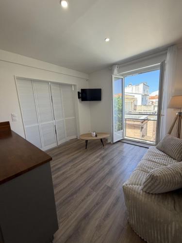 a living room with a couch and a large window at Hôtel The Originals Miramar, Royan Pontaillac in Royan