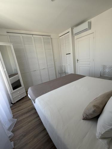a bedroom with a large white bed and a mirror at Hôtel The Originals Miramar, Royan Pontaillac in Royan