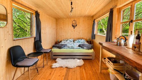 a bedroom with a bed and chairs in a cabin at Tiny house Modřínka in Nadějkov