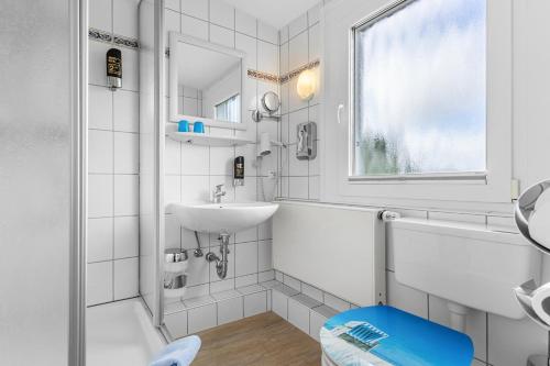 a white bathroom with a sink and a mirror at Hotel Norden Norddeich in Norddeich
