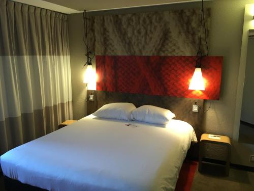 1 dormitorio con 1 cama blanca grande y 2 almohadas en ibis Toulouse Pont Jumeaux en Toulouse