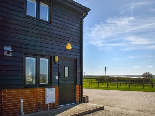 a house with a door and a field in the background at Ivy No1 - Uk49251 in Althorne
