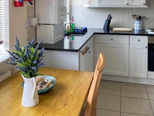 a kitchen with a wooden table with a vase of flowers at Thistle No4 - Uk49250 in Althorne