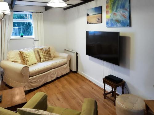 a living room with a couch and a flat screen tv at Kilcummer Stables in Tintagel