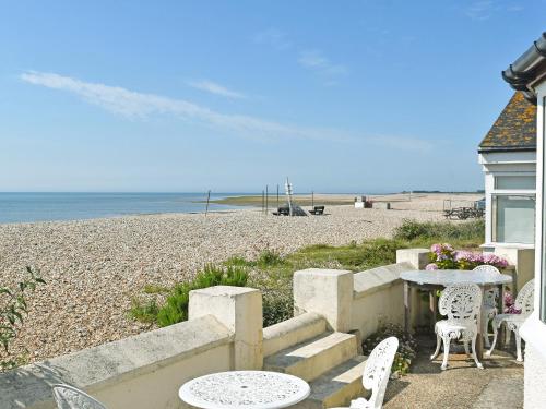 a patio with a table and chairs on the beach at Thalassa in Pagham