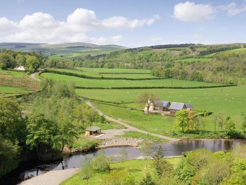 an aerial view of a farm in a field with a river at Pinclanty Cottage in Pinmore