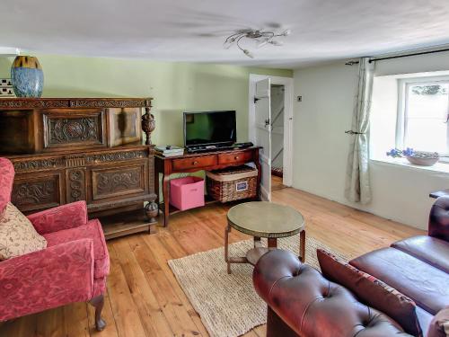 a living room with a couch a table and a tv at Four Oaks in Bransgore