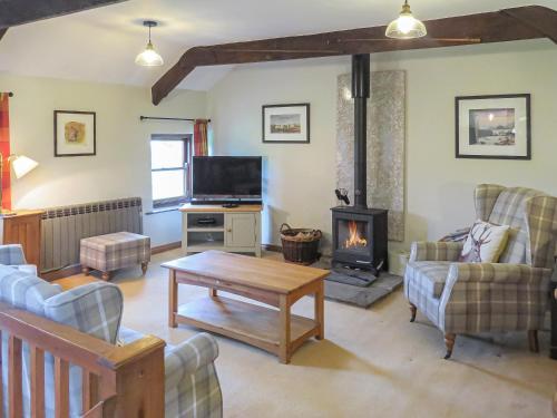 a living room with a fireplace and a tv at 5 Swallowholm Cottages in Richmond