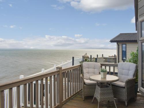 a balcony with two chairs and a table and the ocean at Sunset Lodge in Llanddulas