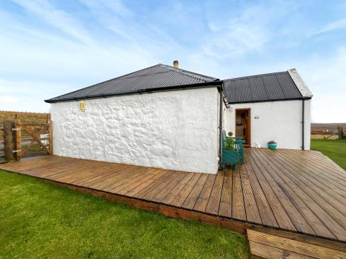 a white building with a wooden deck in the grass at Bothan Aonghais in Portree