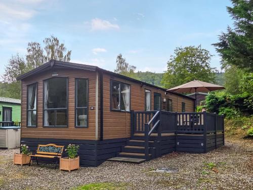 a tiny house with a staircase and an umbrella at 1 Sunview Garden in Birnam
