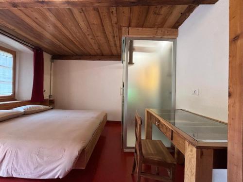 a bedroom with a bed and a desk with a glass table at Riverside Rooms Emma For young and wild spirits in Pontboset