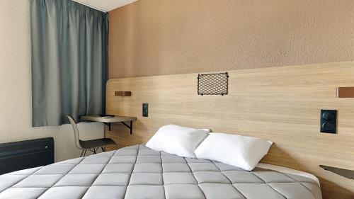 a hotel room with a bed and a desk at Premiere Classe Dreux in Dreux