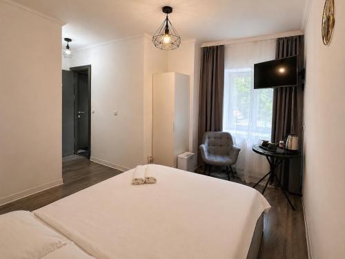 a bedroom with a white bed and a chair at Silver Residence Brașov in Braşov