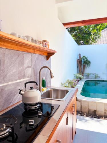 a kitchen with a sink and a tea kettle on a stove at Ajolie Villa in Gili Islands