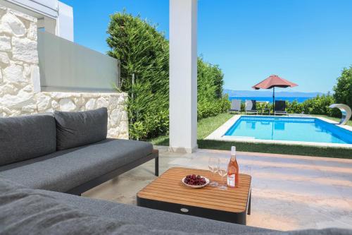 a living room with a couch and a table next to a pool at Villa Mare 2 - Private Pool, Sea View, Starlink, 4 Bdrms in Hanioti