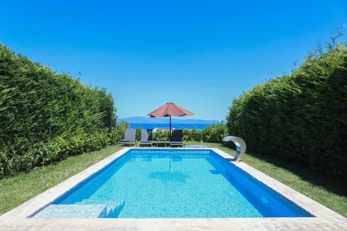 a swimming pool with an umbrella and a table and chairs at Villa Mare 2 - Private Pool, Sea View, Starlink, 4 Bdrms in Hanioti