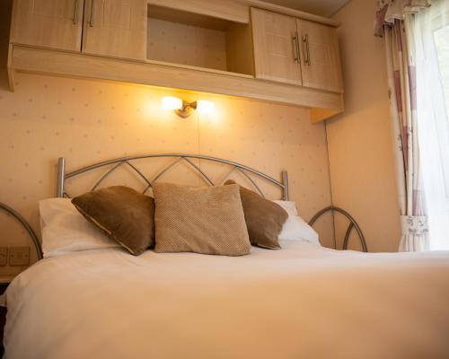 a bedroom with a bed with two pillows on it at The Willows at Kingsmead Camping in West Buckland