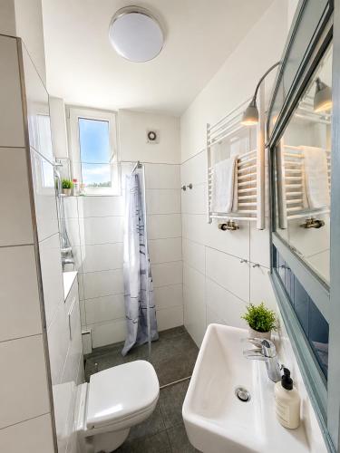 a white bathroom with a sink and a toilet at Velmora Boutique Suites - Vintage Design Apartment in Altstadtnähe in Lübeck