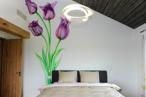 a bedroom with a bed with purple flowers on the wall at als het golft in Roelofarendsveen