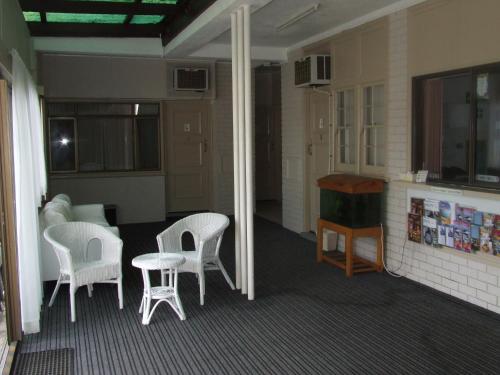 a living room with white chairs and a table at Aquarius Motel in Belmont