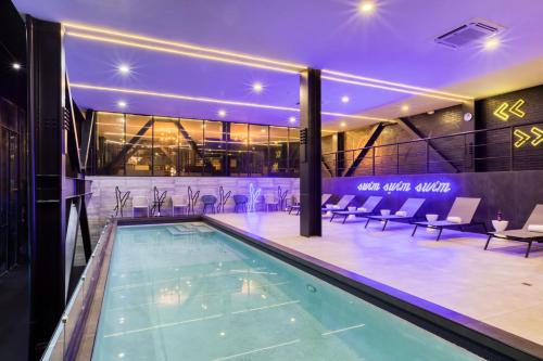 a swimming pool in a building with chairs around it at Downtown Designer Apartments by ULIV in Tijuana