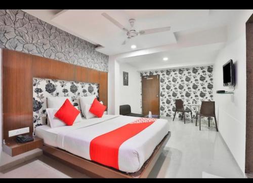 a bedroom with a large bed with red pillows at Hotel keshav in Ahmedabad