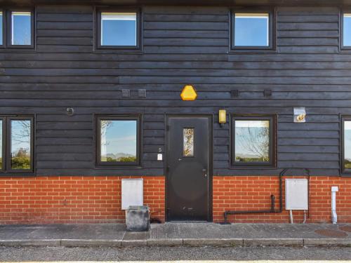 a house with a black door and a brick wall at Periwinkle No5 - Uk49249 in Althorne