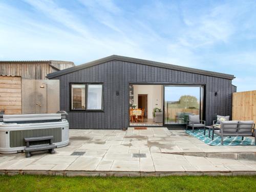 a black house with a patio and a hot tub at Hernmargh Skiber in Marhamchurch