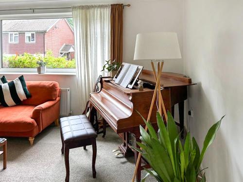 a living room with a piano and a couch and a window at Views Wood in Uckfield