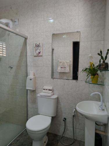 a white bathroom with a toilet and a sink at Urca do Tubarão in Touros