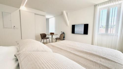 a white bedroom with a bed and a table at Studio Premium Climatisé in Avallon