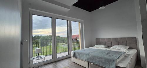 a bedroom with a bed and a large window at Villa nad stawem in Pszczew