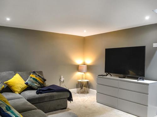a living room with a couch and a flat screen tv at Doodles Holiday Home in Eyemouth