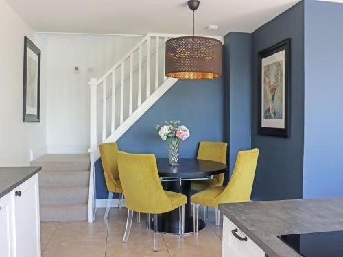 a dining room with a table and yellow chairs at Deerview Lodge - Uk51044 in Bonvilston