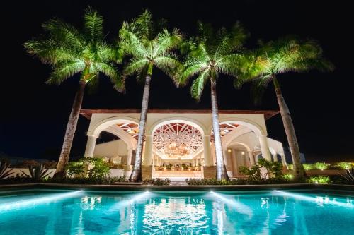 a villa with palm trees and a swimming pool at night at Wyndham Alltra Punta Cana All Inclusive Resort in Punta Cana