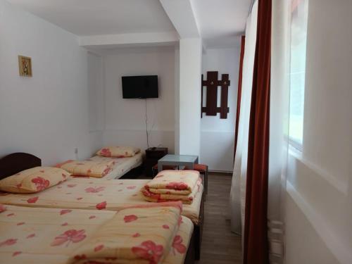 a room with two beds and a tv on the wall at Gutza Family in Cumpăna