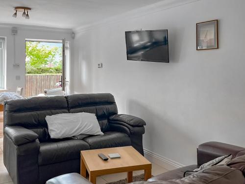 a living room with a couch and a tv on the wall at Mistletoe No3 -Uk49252 in Althorne