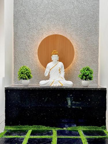 a statue of a buddha with two plants at Meadows Homestay Elite in Madurai